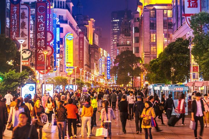 Crowds of shoppers mingle under the lights of a shopping street in Shanghai